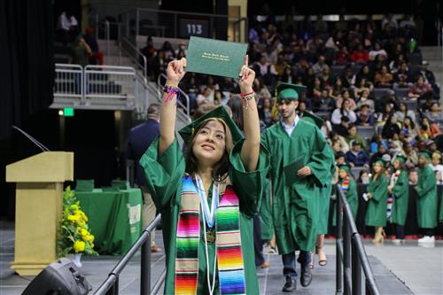 Student holds up her diploma at graduation
